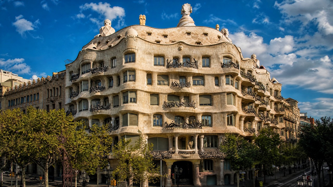 Casa Milà is a residential building in Barcelona designed by Gaudí, famous for its undulating stone facade and sculptural chimneys; a World Heritage Site.
